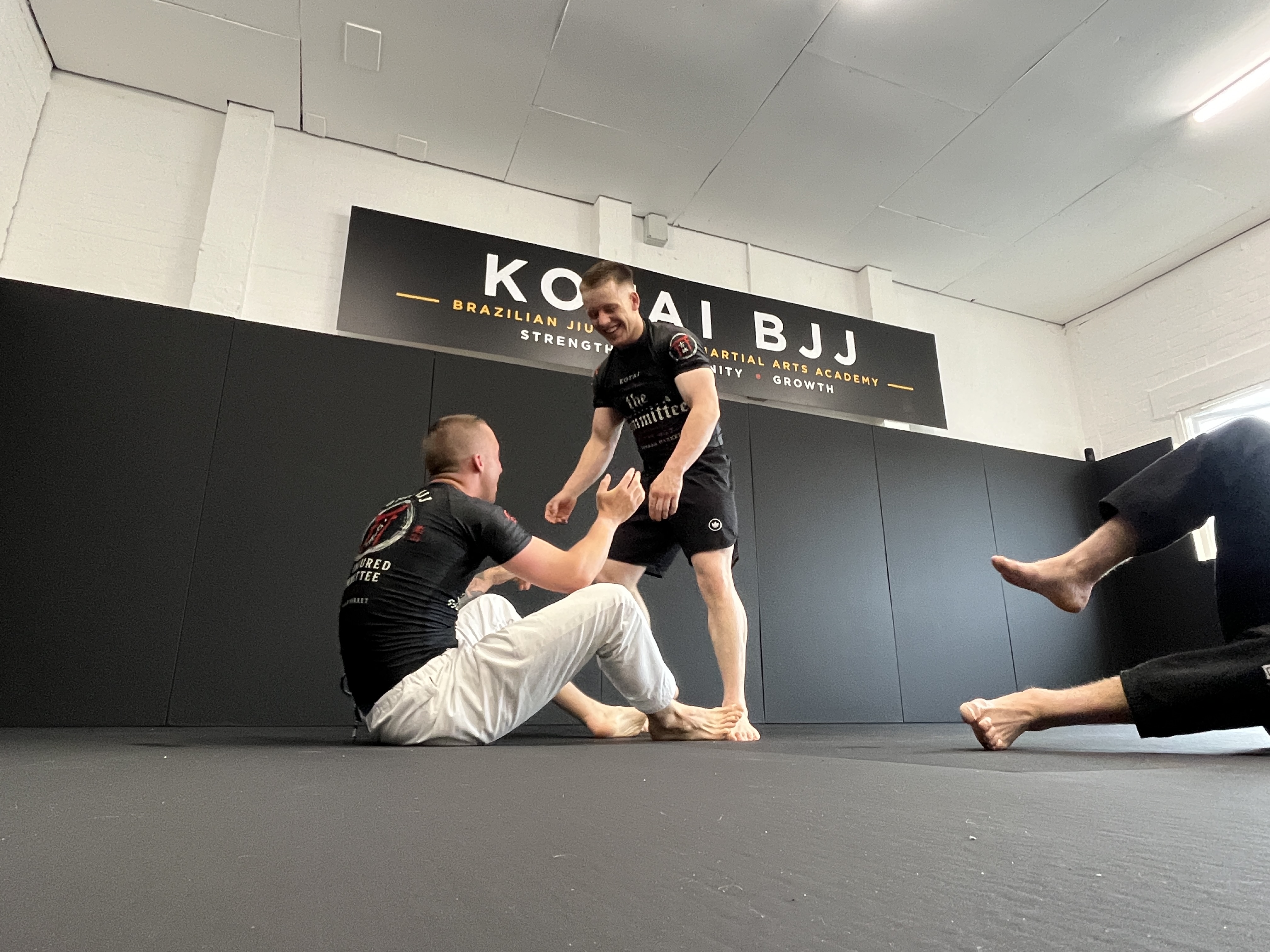 Two members resetting after a round beneath the Kotai BJJ academy sign